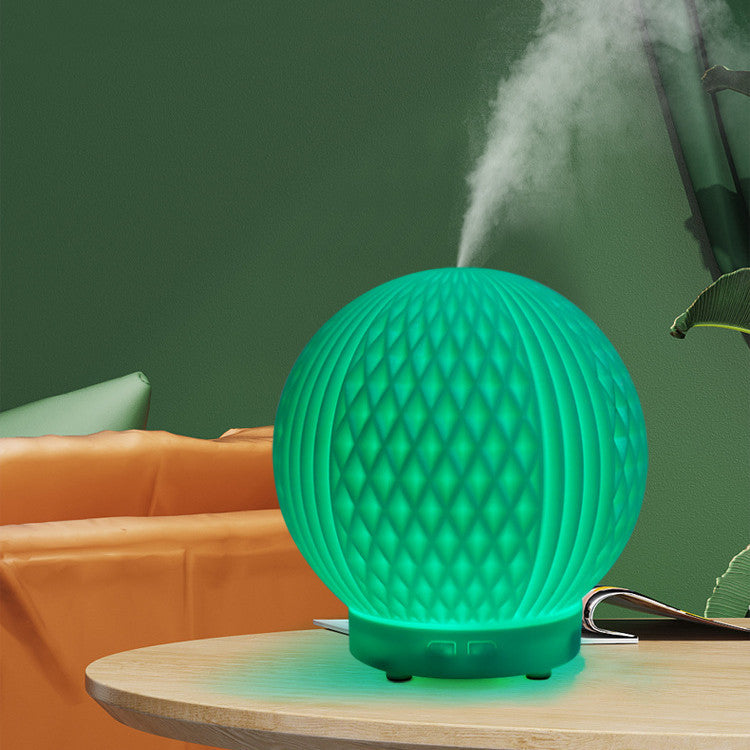 Sheila Merchandise automatic essential oil diffuser in green emitting mist on wooden table in living room