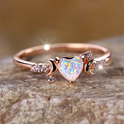 Rose gold moonstone love ring with heart-shaped gem and crescent moon details on stone surface
