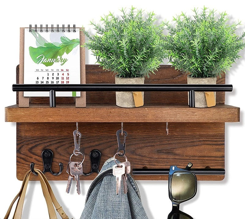 Sheila Merchandise wall-mounted wooden shelf with hooks, holding keys, sunglasses, calendar, and small potted plants